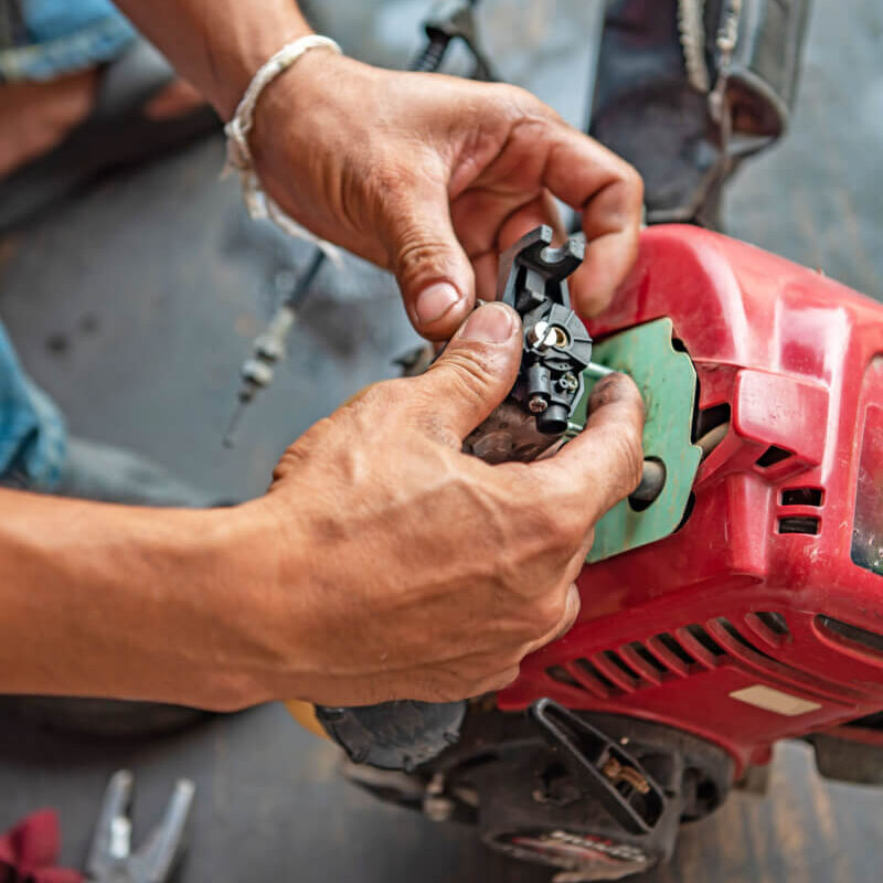 stock-photo-repairman-fixes-the-lawn-mower-engine-with-tools-at-the-workshop-1700886400